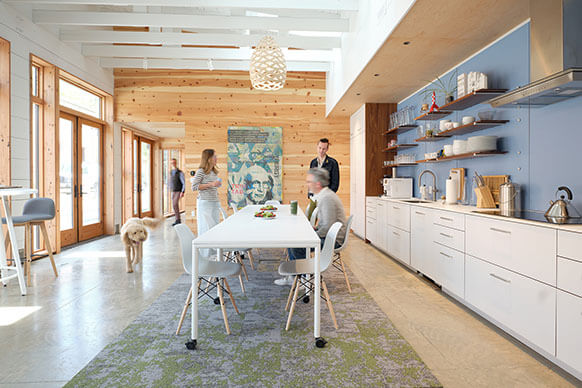 interior of the studio's dining room, with a group of people and a dog gathered around