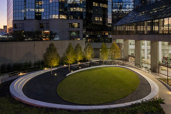 Looking into the lighted sculptured seating wall and elliptical lawn of the Atlanta Financial Center courtyard at night