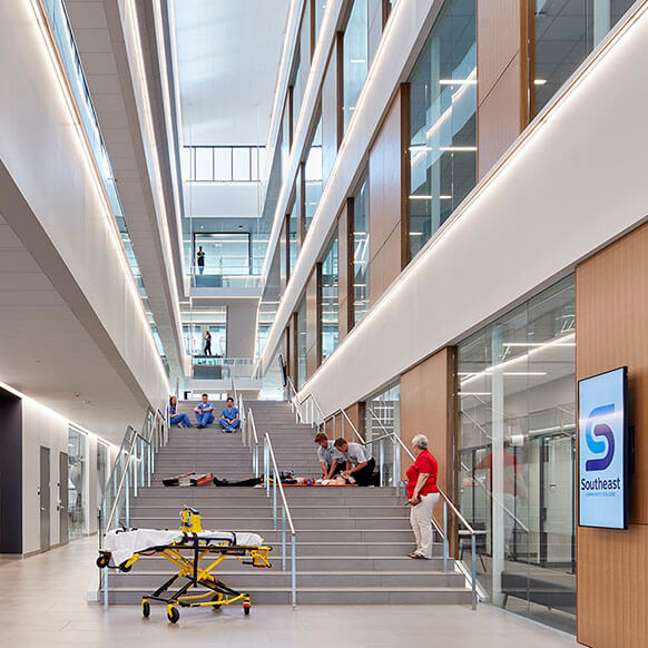 Photo of health sciences students and instructor conducting medical emergency simulation in a large, open atrium