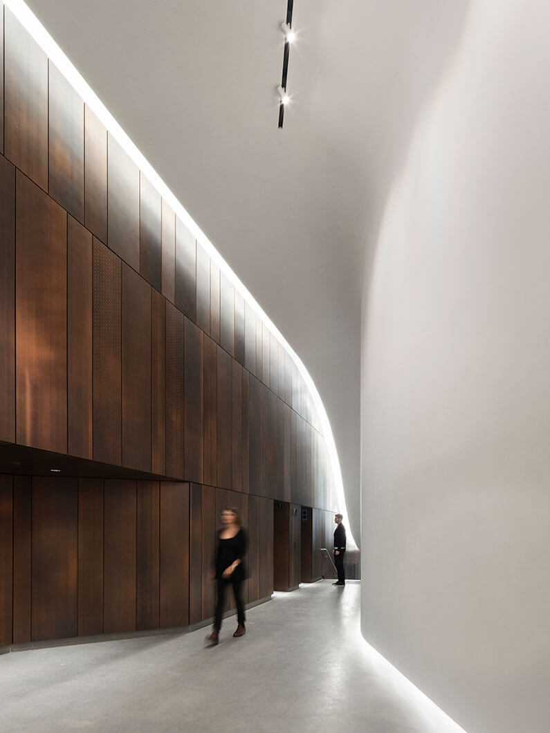 Photo of person walking through lobby with another individual waiting at the elevator.