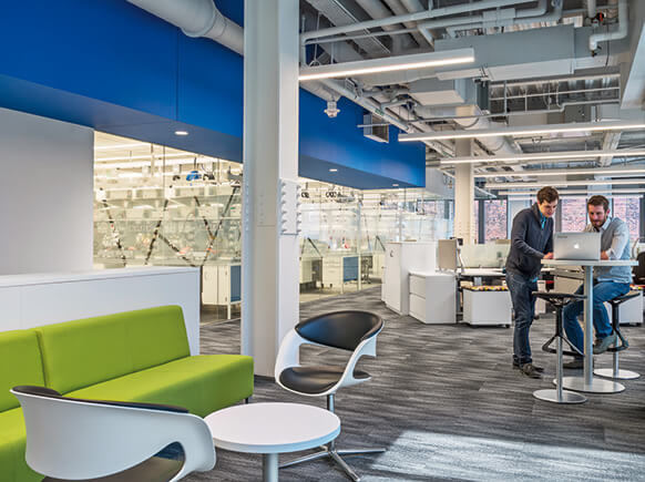 office space with windows to lab areas and two people working