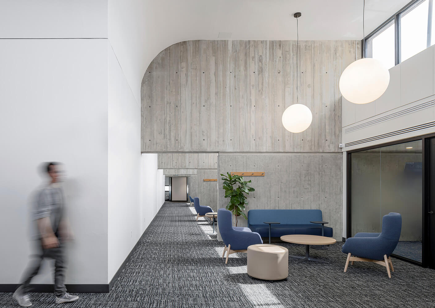 A hallway with curved, concrete partitions and orb lights