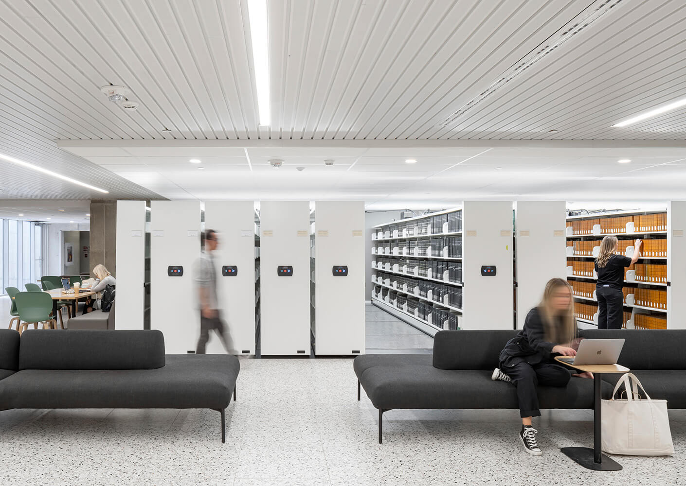 A room with black couches and sliding shelves containing books